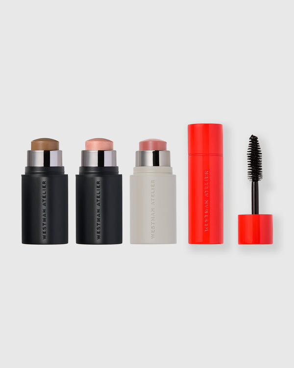 Set of petite makeup products including a Face Trace Contour Stick, Lit Up Highlight Stick, Baby Cheeks Blush Stick, and petite Eye Want You Mascara on a light gray background.