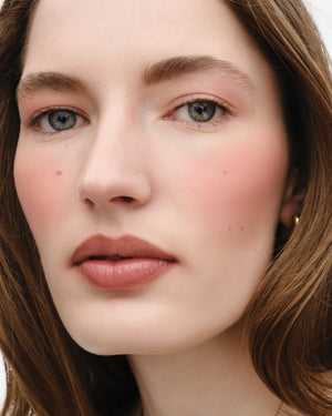 Model wears the Baby Cheeks Powder Blush Duo in Suede / Sable. 