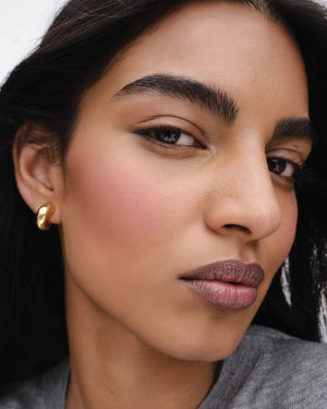 Model wears Baby Cheeks & Face Trace Sculpting Powder Duo in Tulle / Truffle. 