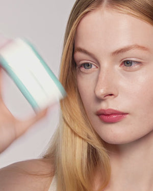 Blonde model applies bronzing drops.
