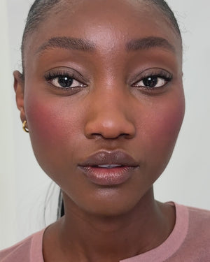 Model applies the Baby Cheeks Powder Blush Duo in Jam/Fizz. 